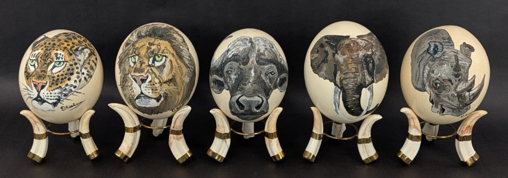 (5) The Big Five Painted African Ostrich Eggs w/ Boar Tusk Stands: Very unique pieces with hand painted images of the big five African animals mounted on authentic boar tusks with copper hardware. All pieces are in very nice condition. Measures 9in tall. Ref #: 551