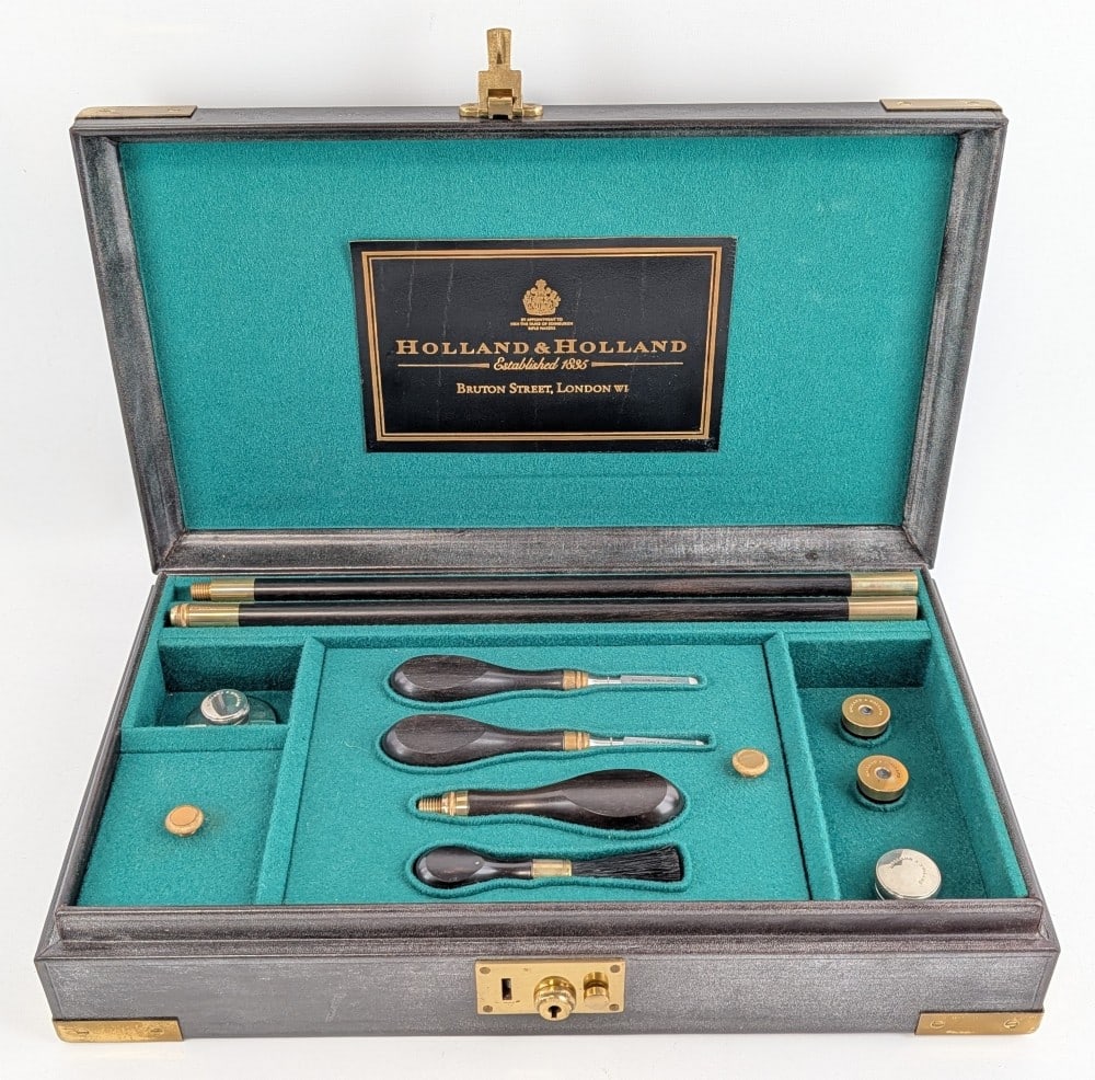 Holland & Holland 12 Ga Shotgun Cleaning Kit: Includes a 32-1/2in cleaning rod, various kinds of brushes, cleaning patches, oilers, snap caps, and a branded soft cloth. All of the pieces are stamped with the Holland & Holland banner. Kit is in li