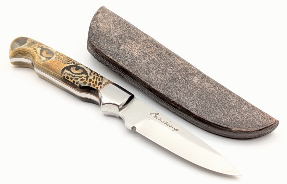 Gaetan Beauchamp Scrimshaw Horn Utility Hunter w/ Sheath: Features a satin finish blade, high polish steel bolsters, and gorgeous scrimshaw horn handle scales with a leopards staring eyes on one side and paws on the other. Comes with the original leather she