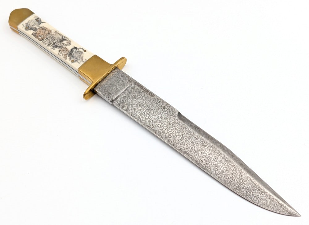 Charlton LTD Damascus Scrimshaw Exotic Bone Bowie Knife: Features a damascus blade, brass double guard, brass bolsters, and scrimshaw exotic bone handle scales with African animals signed Brady possibly Sandra Brady. Knife is in like new condition. Blade le