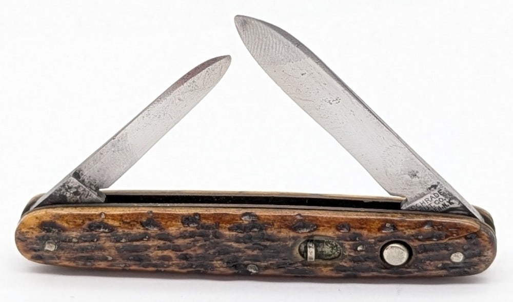 Schrade Cut Co. Jigged Bone 2-Blade Switchblade Knife: Knife is in fair cleaned condition with material loss and scratches on the polished blades, and a pin crack across the front handle scale. Both blade springs are strong, and lock tight when open. Over