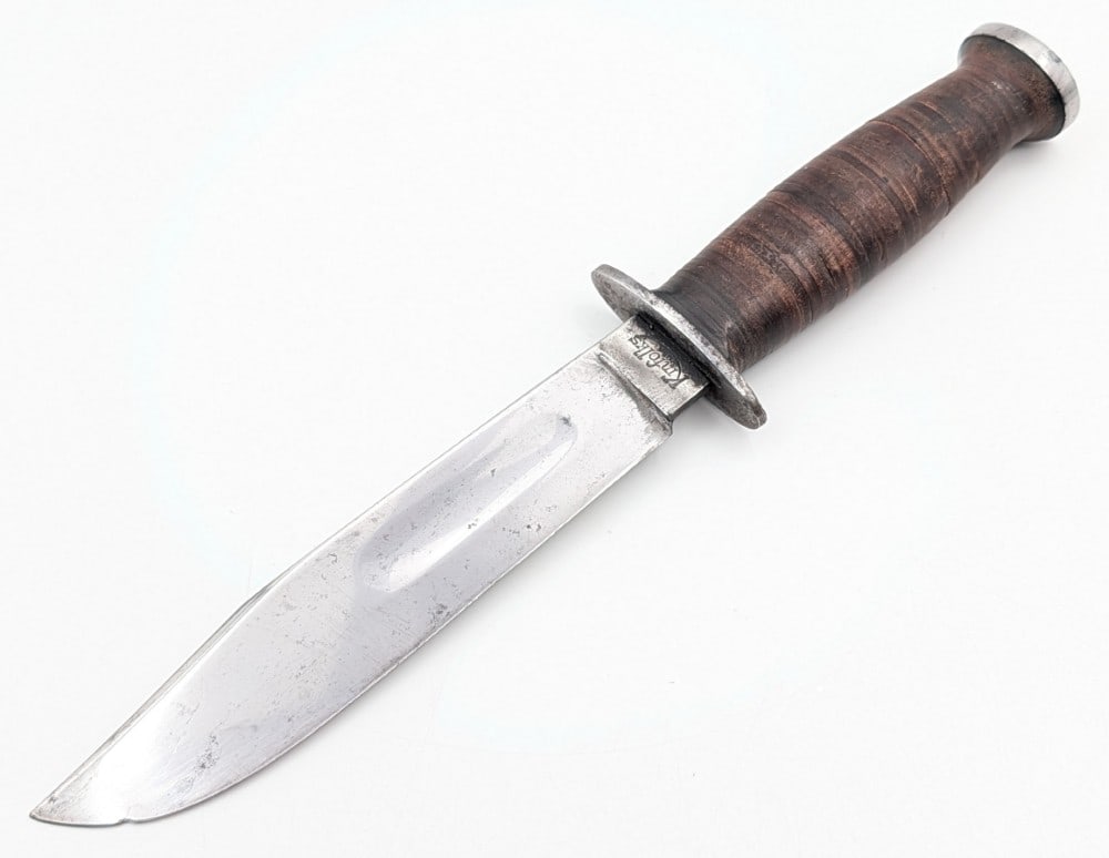 WWII Kinfolks Fighting Knife: Features a mirror polished clip point blade, double steel guard, stacked leather handle, and steel pommel. Knife is in good cleaned condition with scratches and carbon spots on the blade, and scratche