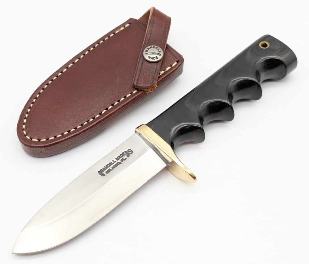 Randall Finger Groove Micarta Fireman Special w/ Sheath: Features a stainless steel blade with thumb notches, a brass single downturned guard, and a black micarta finger groove handle with a lanyard hole. Knife is in like new condition. Blade length measure