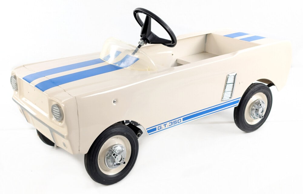 Contemporary Ford Mustang Pedal Car: Reproduction Ford Mustang pedal car. The car is missing the Mustang badge and shift lever. The car shows light wear from storage and display. Measures approximately 39" long.