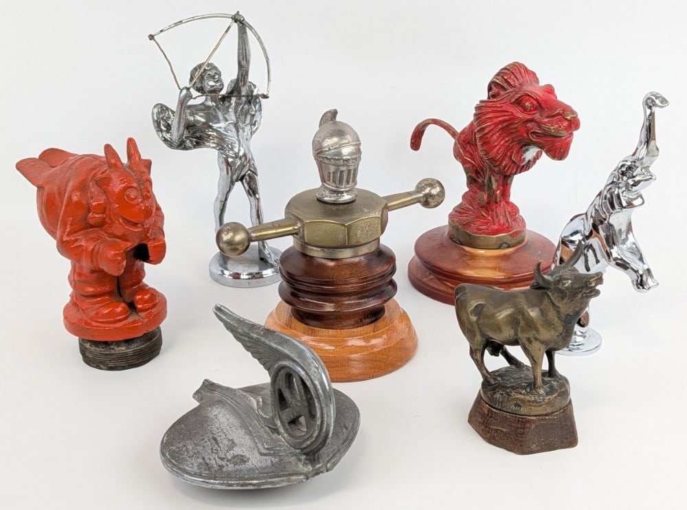 Group of (7) Car Mascots: Includes "Tireur d'Arc", 1932-1933 Studebaker Rockne, Doc Yak, Willy's Knight,? Bugatti Type 41 Royale "Dancing Elephant", Lion, and Cow.? Largest measures 8" tall.