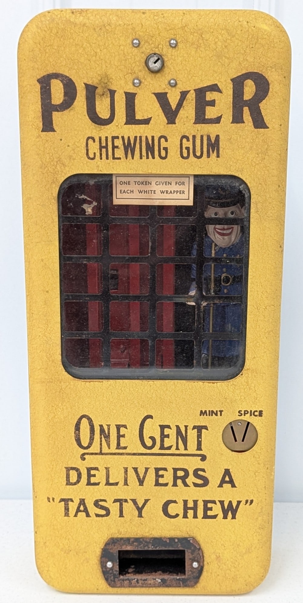 Vintage Pulver 1 Cent Police Officer Yellow Gum Vendor: Vintage Pulver 1¢ mechanical Police Officer sign turning gum wall mount vending machine. Appears to be in good working condition with some paint loss, surface rust, and wear from use and age. Police