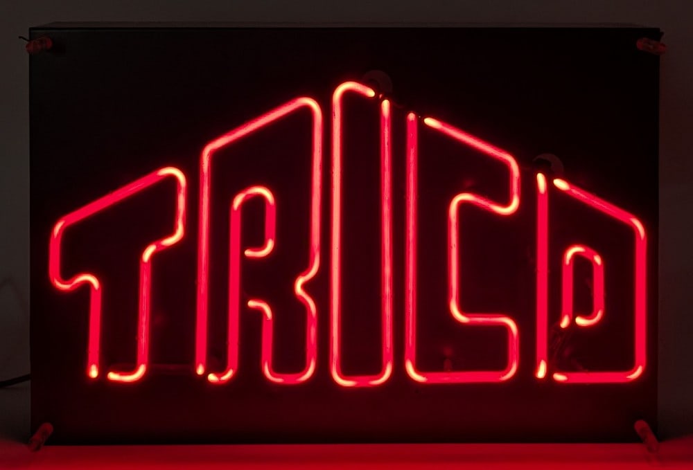 Trico Wiper Blades Neon Advertising Sign: Trico wiper blades neon advertising sign. The sign displays well when lit with the color red neon. The metal can has some paint starting to bubble. The metal can measures approximately 24" across by 1