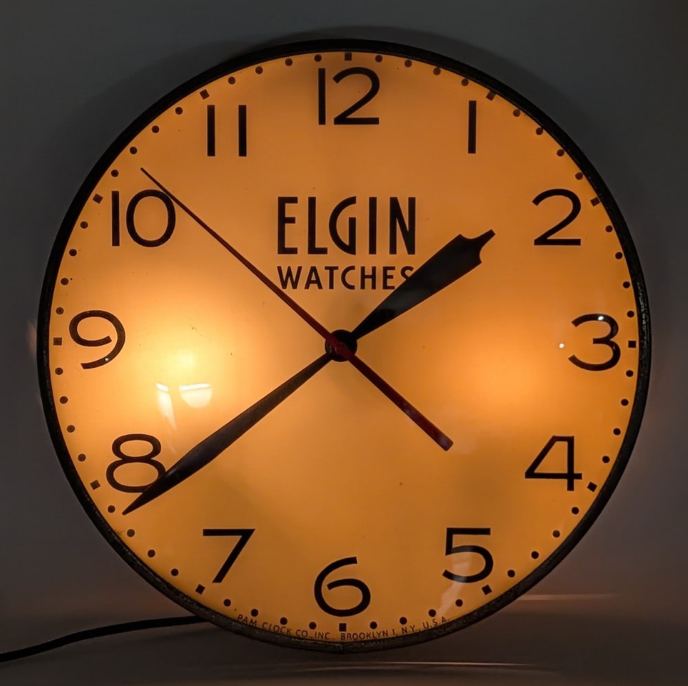 Vintage Elgin Watches Lighted Advertising PAM Clock: Vintage Elgin Watches lighted advertising PAM clock. The clock lights up and worked when tested. It does have some surface rust to the metal ring and wear from use and age. Measures approximately 14-1