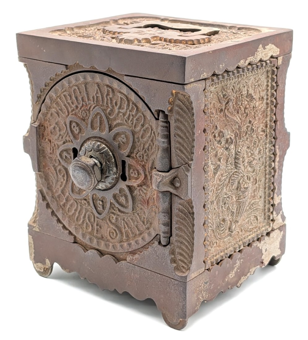 J&E Stevens Cast Iron Burglar Proof House Safe Still Bank: J&E Stevens cast iron burglar proof house safe still bank. The bank shows plating loss and wear from use and age. No keys included. Measures approximately 6" tall by 4-3/4" across by 4-1/4" deep.