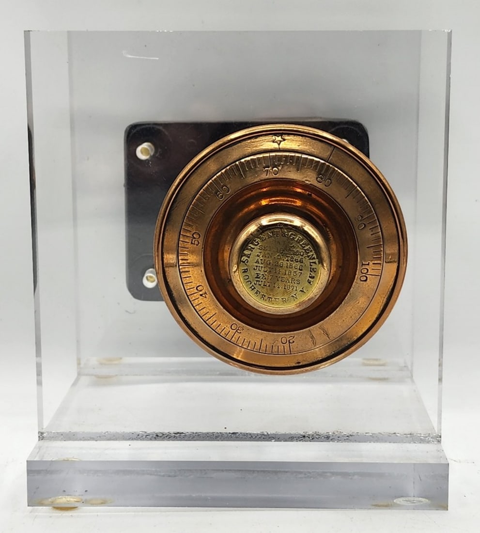Sargent & Greenleaf Safe Lock Mechanism Acrylic Display: Sargent & Greenleaf is a company based in Rochester N.Y. The Lock was first patented on September 18, 1860. It features a dial combination lock and black cast metal plate. Metal is worn due to age and