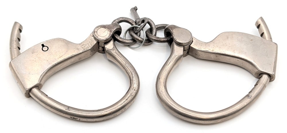 Tower's Handcuffs w/ Key: Tower's Handcuffs with key. The handcuffs show some plating loss and wear from age.