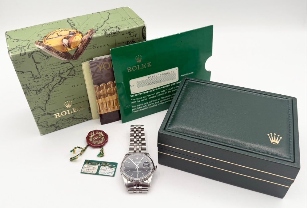 1990 Men's Rolex Stainless Datejust Oyster Perpetual Wristwatch In Box: 1990 Men's Rolex Stainless Datejust Oyster Perpetual Wristwatch #16220. Watch has a tight jubilee bracelet. It features a black dial, automatic movement, and date at 3 o'clock. It measures 36mm. Seria