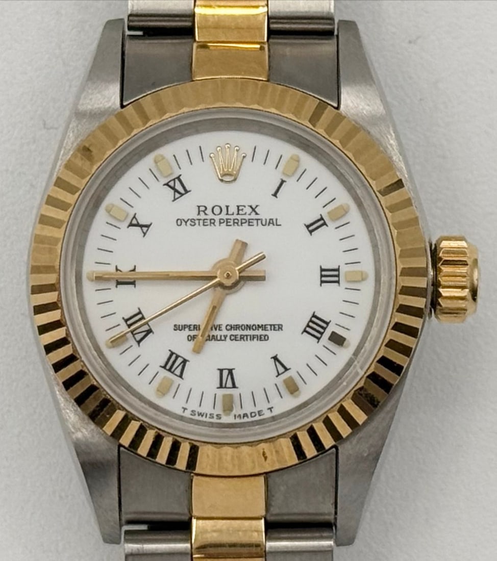 Ladies Rolex Two-Tone Roman Numeral Dial Oyster Perpetual Wristwatch: Ladies Rolex Two-Tone Oyster Perpetual Wristwatch #67193. Watch and the bracelet are 18K yellow gold and stainless. It features a white Roman numeral dial and automatic movement. It measures 26mm and
