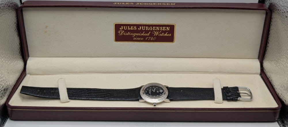 Ladies Jules Jurgensen 14k White Gold Watch: Ladies Jules Jurgensen 14k White Gold Watch. The quartz movement watch has a black face with a diamond at 12 o'clock. The round case measures approximately 27mm in diameter. The case is solid 14k gold