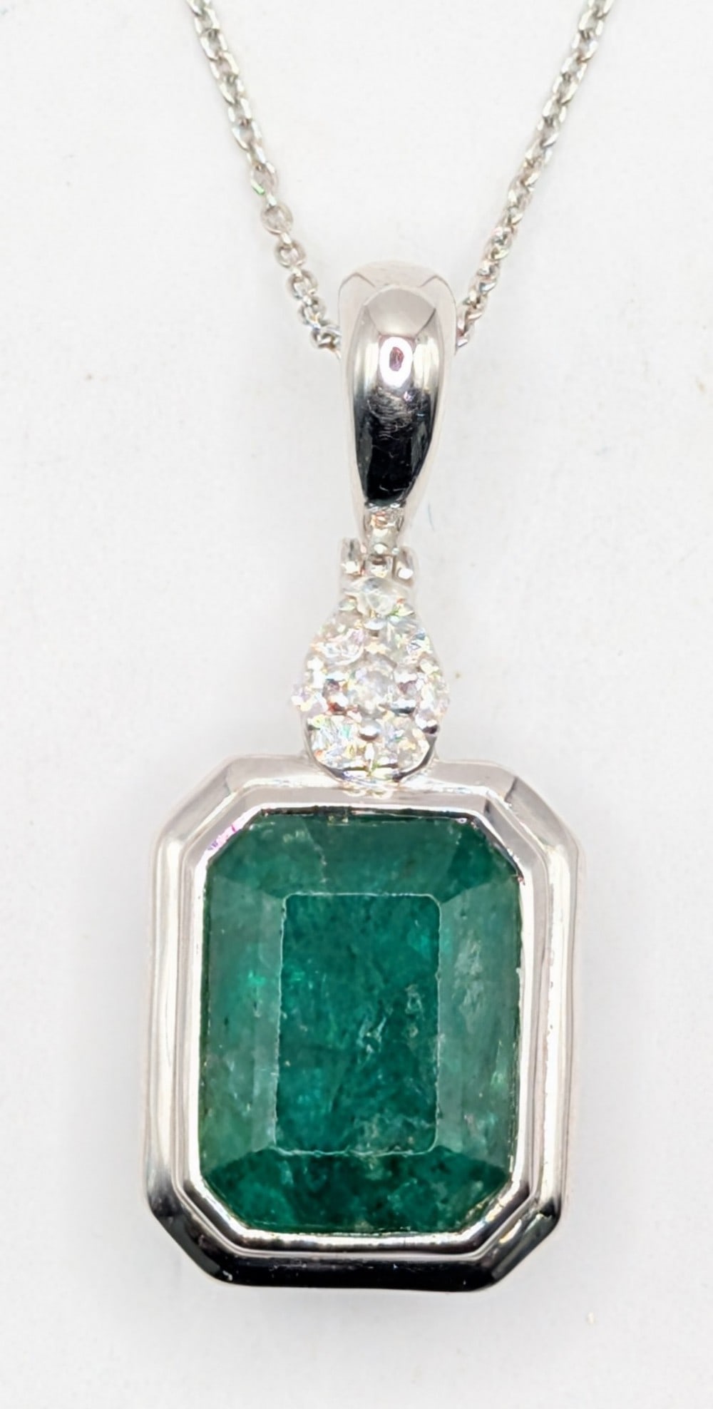 Platinum Oscar Friedman Emerald & Diamond Pendant Necklace: Platinum designer Oscar Friedman pendant necklace with 6.47 CT emerald and (8) round cut diamonds totaling 0.14 CTS. Pendant is on a 18" platinum chain and total weight is 8.1 grams. Necklace comes wi