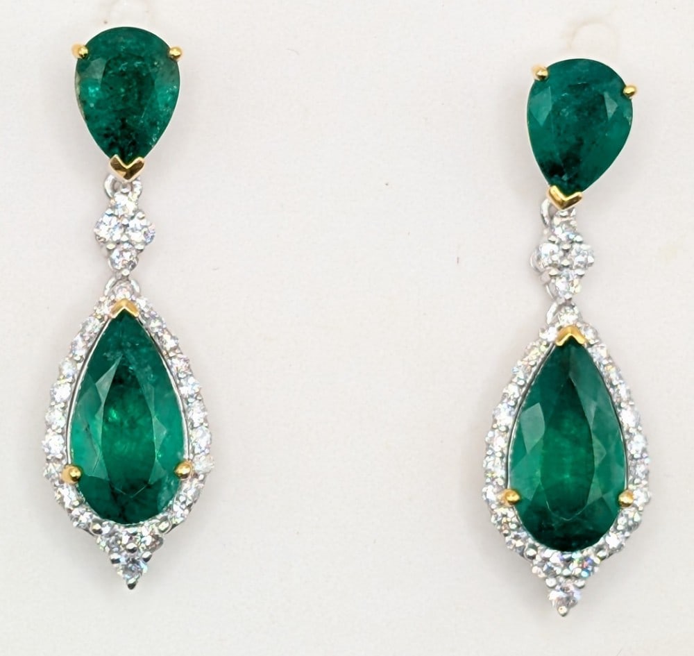 Platinum & 18K Gold Emerald & Diamond Drop Earrings: Platinum and 18K yellow gold drop earrings with (4) pear cut green emeralds totaling 5.42 CTS and (28) round cut diamonds totaling 0.70 CTS. Earrings weigh 8.3 grams. Earrings come with a Gemassure ge