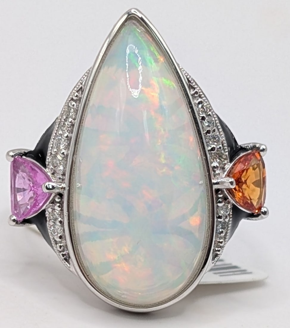 Platinum Pear Cut Opal & Sapphire Ring: Platinum ring with 8.81 CT pear cut cabochon opal and (2) trillion cut pink and orange sapphires totaling 1.03 CTS and (12) round cut diamonds totaling 0.09 CTS. Ring is size 7.5 and weighs 8.7