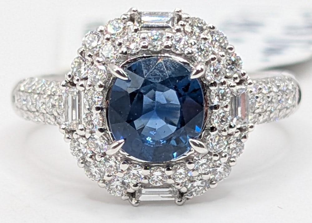 Platinum Oval Blue Sapphire & Diamond Halo Ring: Platinum ring with 1.33 CT oval cut blue sapphire and (66) baguette and round cut diamonds totaling 0.93 CTS. Ring is size 6.5 and weighs 5.5 grams. Ring comes with an AIGL appraisal report with an