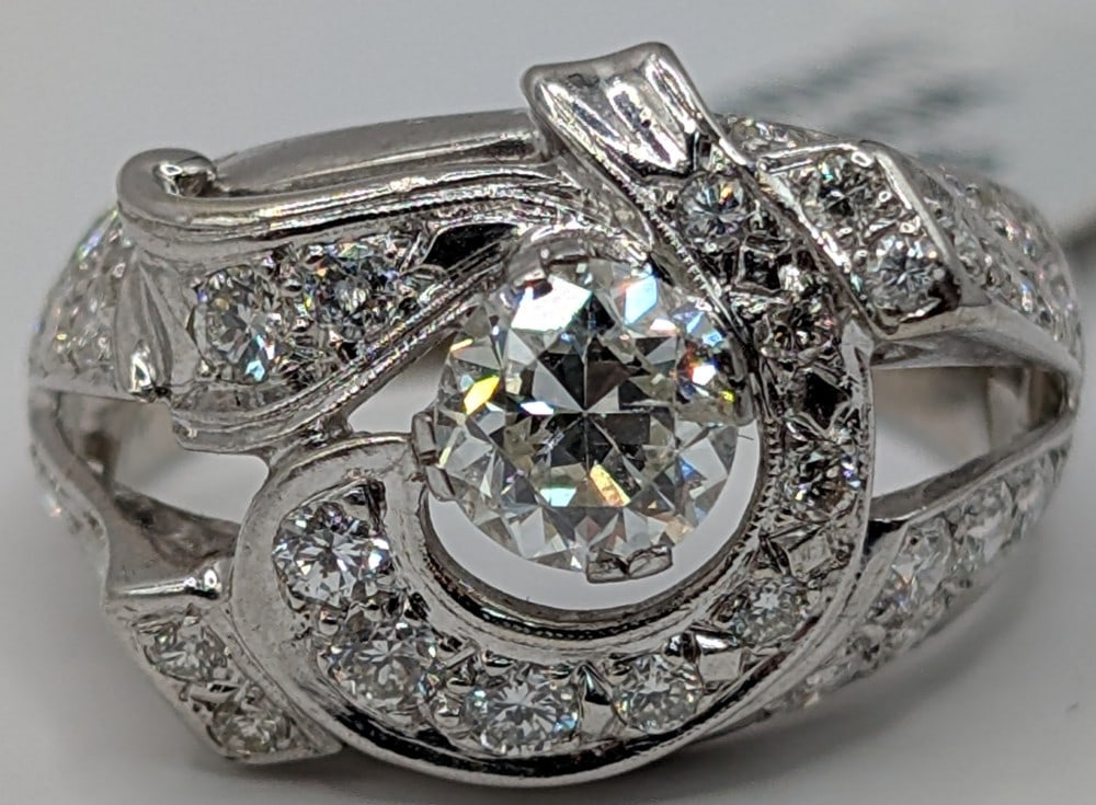 14K Gold Diamond Swirl Ring: 14K white gold ring with 0.75 CT round cut diamond center stone and (38) round cut diamond accents with a total of 1.00 CT.? Ring is size 7 and weighs 4.89 grams. Ring comes with an AIG estimated reta