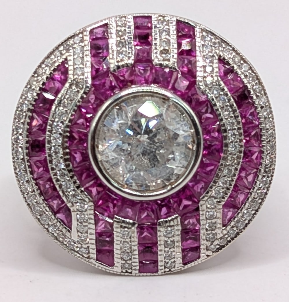 18K Gold 1.50 CT Center Diamond & Ruby Ring: 18K White Gold 1.50 carat center diamond ring with (68) square cut rubies and (128) round cut diamonds. The center diamond has a color grade of J and a clarity grade of I1. The ring size is size 7 and