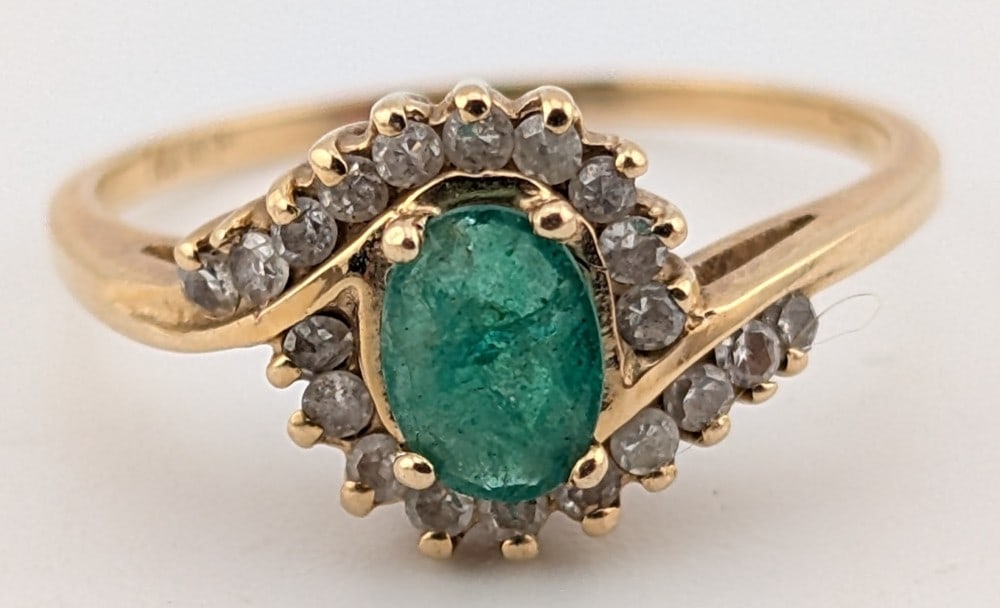 14K Gold Emerald & Diamond Ring: 14K yellow gold ring with oval cut emerald and round cut diamond swirl halo. Ring is size 7 and weighs 2.3 grams.