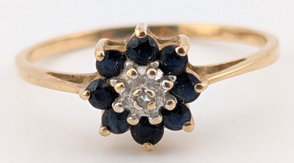 10K Gold Sapphire & Diamond Floral Ring: 10K yellow gold ring with diamond center stone and dark blue sapphire "petals". Ring is size 7 and weighs 1.2 grams.