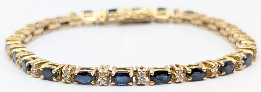 14K Gold Blue Sapphire & Diamond Tennis Bracelet: 14K yellow gold tennis bracelet with (48) round diamonds and (24) oval blue sapphires. Diamonds total 0.62 CT and sapphires total 8.4 CT. Bracelet measures 8" and weighs 14 grams. Bracelet was apprais