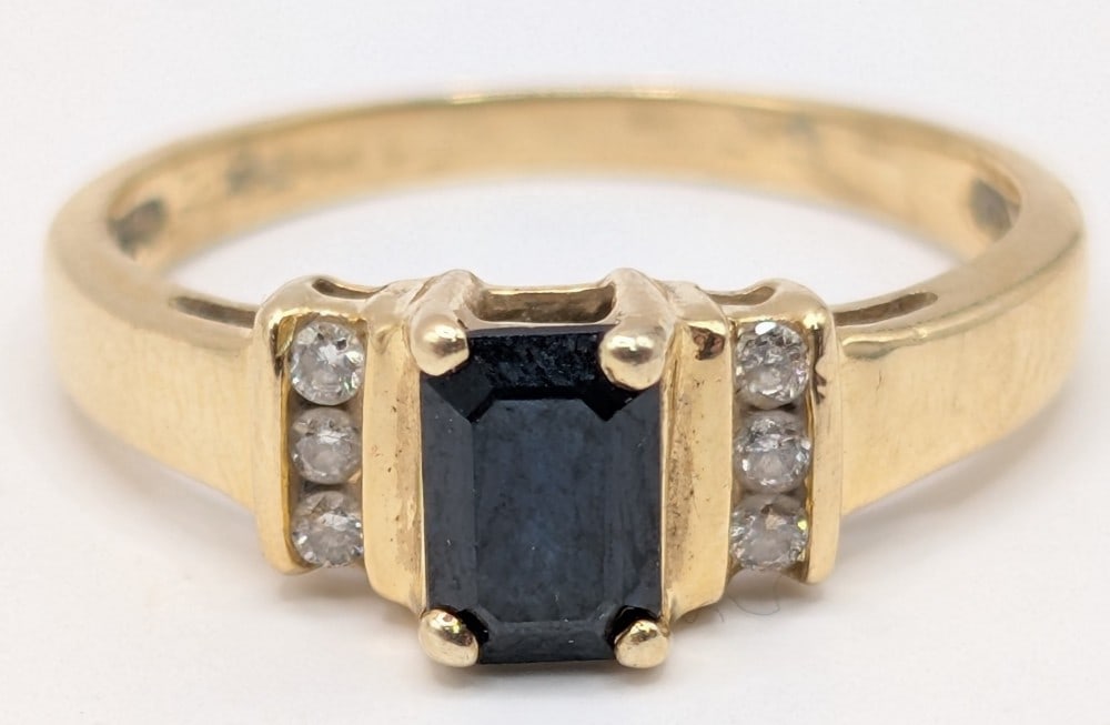 14K Gold Emerald Cut Sapphire & Diamond Ring: 14K yellow gold ring with emerald cut dark blue sapphire and channel set round cut diamond accents. Ring is size 6 and weighs 2.5 grams.