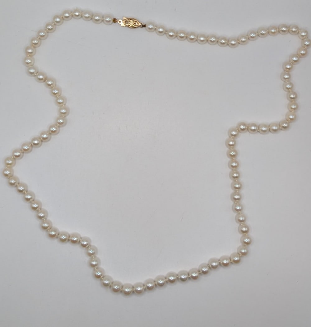 14K Gold Clasp Pearl Necklace: 14K yellow gold clasp hand tied pearls necklace. Measures 22"