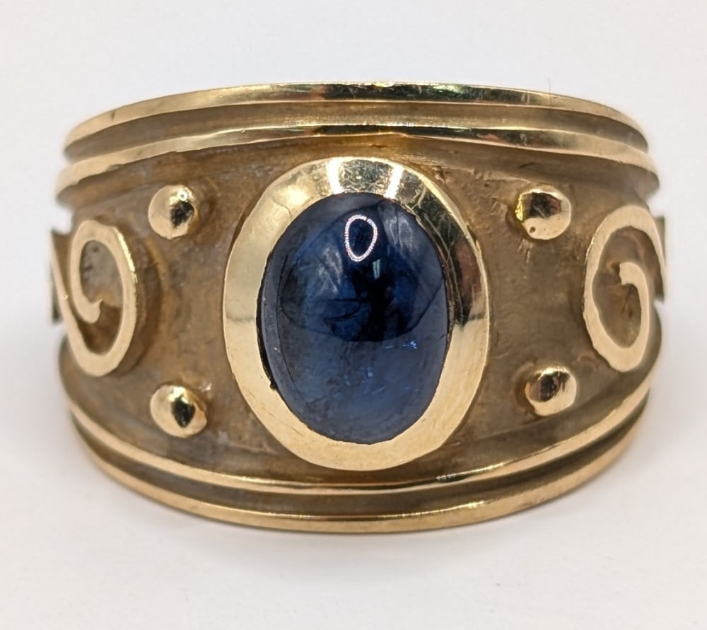 14K Gold Blue Sapphire Ring: 14K yellow gold wide band ring with oval cabochon blue sapphire stone. Ring is size 6 and weighs 7.3 grams.