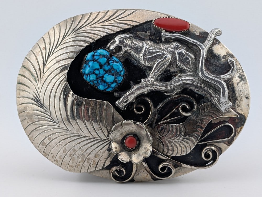 Vintage Sterling Native American Turquoise & Coral Bobcat Belt Buckle: Vintage sterling silver Native American made and signed JK belt buckle depicting a bobcat in a tree with turquoise and coral stones. Belt buckle measures 3" by 4" and weighs 109 grams.