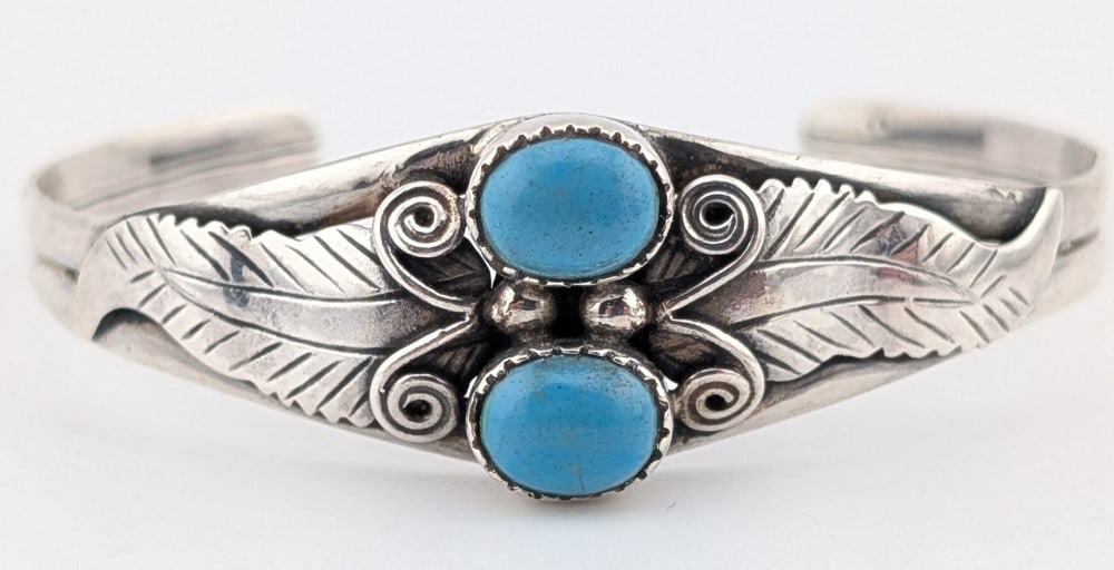 Vintage Sterling Native American Turquoise Cuff Bracelet: Vintage Native American sterling silver feather design cuff with two oval cabochon turquoise stones. Cuff weighs 13 grams.