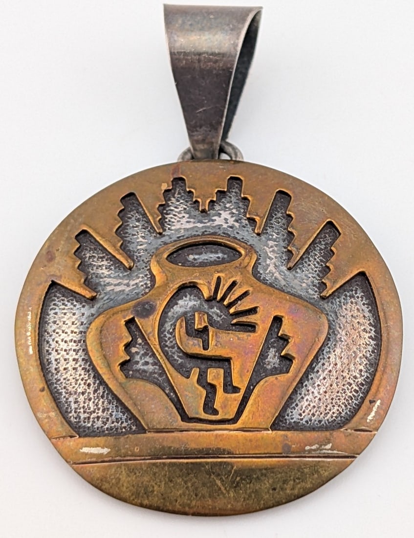 Signed Daniel Mike Navajo Sterling Silver & 12k Gold Filled Kokopelli Pendant: Handcrafted sterling pendant by the esteemed Navajo artist Daniel Mike. This piece features his signature "Storyteller" aesthetic, executed in a high contrast mixed-metal overlay. The circular pendant