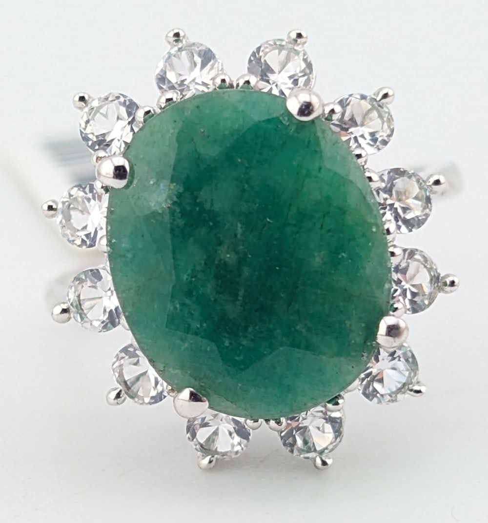 Sterling Emerald 6.50 ctw & Sapphire Halo Ring: Sterling silver oval cut dyed green beryl (emerald) with round cut white sapphire halo. The emerald is 6.50 ctw and the white sapphire corundum halo is 1.50 ctw. The ring comes with a CGA registered a