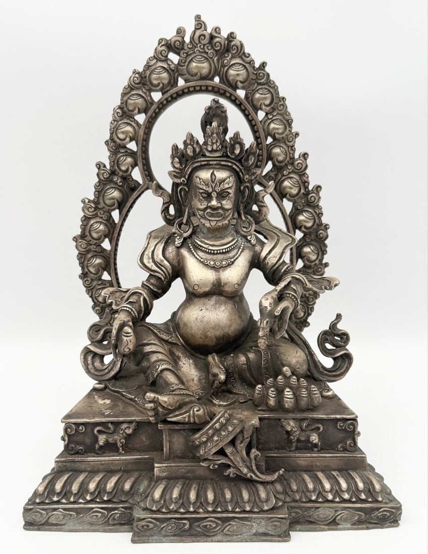Antique White Metal Jambhala Buddhist God Of Wealth Statue: Antique White Metal Jambhala Buddhist God Of Wealth Statue. The statue has fine detail with some age and display wear, has some green patina in spots. Marked on the base. Measures approximately 10" ta