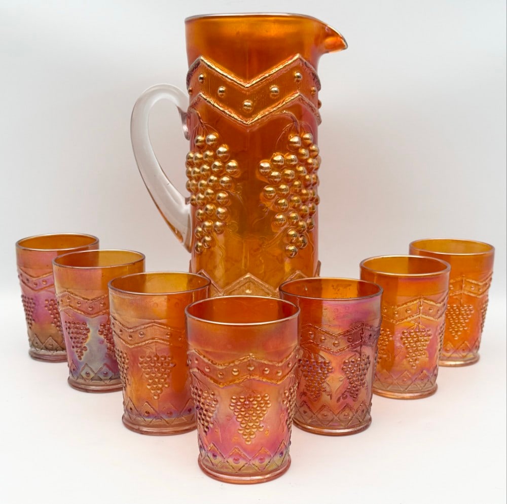 1900's Fenton Carnival Glass Grapes & Lattice Marigold 8-Piece Water Set: 1900's Fenton Carnival Glass Grapes & Lattice Marigold 8-Piece Water Set. The set includes the water pitcher and seven tumblers. The set is in good condition with no chips or cracks. The pitcher measu