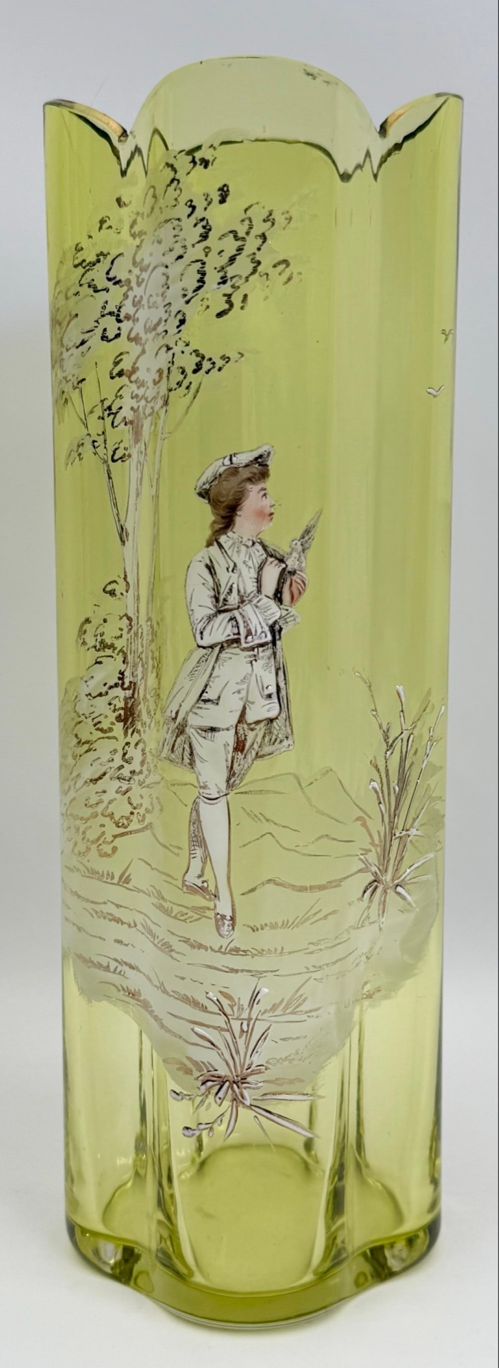 Victorian Mary Gregory Style Enamel Painted Yellow Glass Vase: Victorian Mary Gregory Style Enamel Painted Yellow Glass Vase. The vase features a young man holding a bird while taking a walk. Good vintage condition with some wear to the gold accents on the top ed