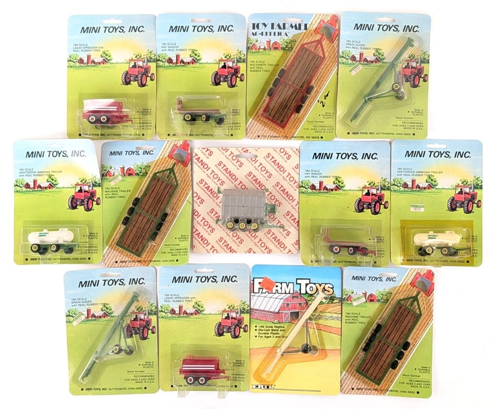 (13) 1/64 Custom Mini Toys & Standi Toys Farm Implements / Accessories: (13) 1/64 scale farm implements. Includes Mini Toys hay wagons, trailers, grain augers, anhydrous ammonia tanks, and Standi Toys grain dryer. Good condition in the packages.