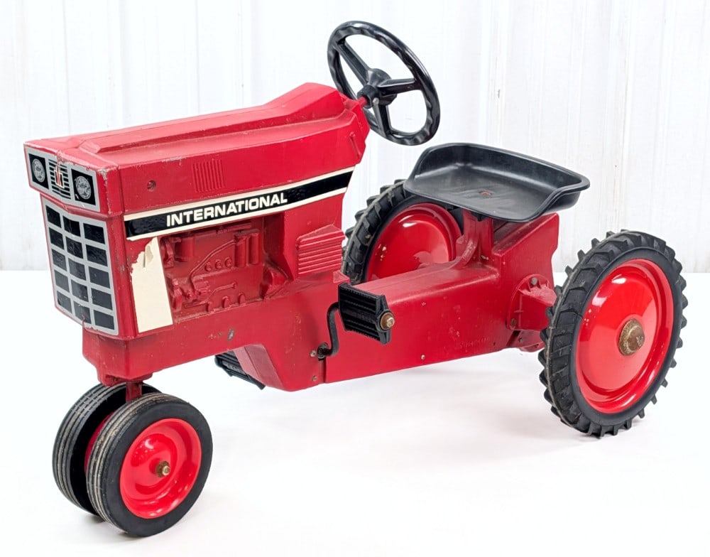 Ertl International Narrow Front Pedal Tractor: Ertl International narrow front pedal tractor. The tractor appears to have an old restoration. It is missing one of the rear hubcaps, has scratches, surface rust, and wear from age. Measures approxima