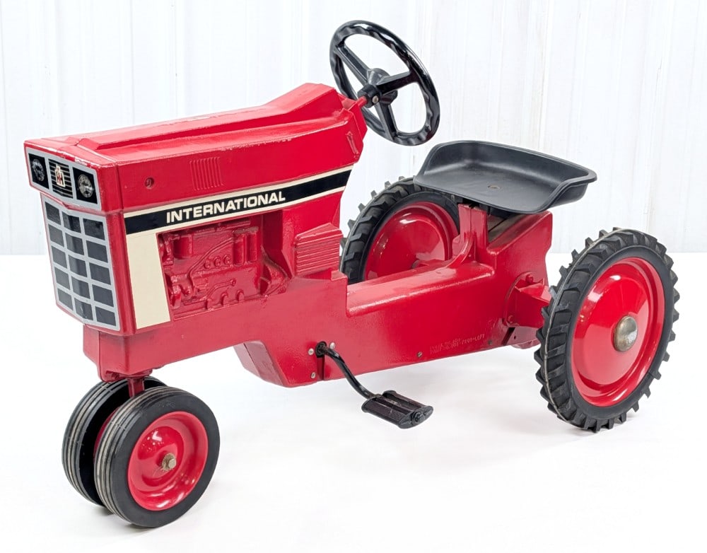 Ertl International Narrow Front Pedal Tractor: Ertl International narrow front pedal tractor. The tractor appears to be original with paint loss, surface rust to the chrome hubcaps, and wear from use / age. Measures approximately 37" long.