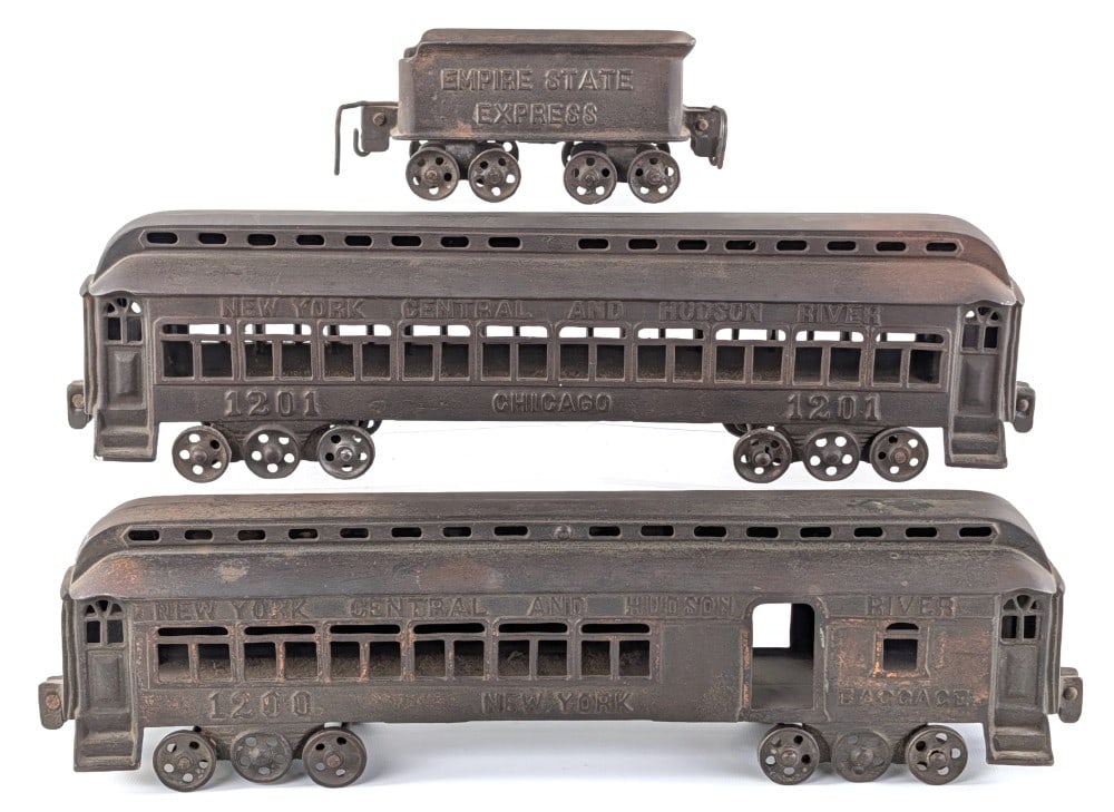 Kenton Cast Iron Empire State Express Tender & NYC & HR Passenger Cars: Kenton cast iron Empire State Express tender and New York Central and Hudson River 1200 / 1201 passenger cars. The passenger cars are missing wire couplers. Each car measures approximately 16" across.