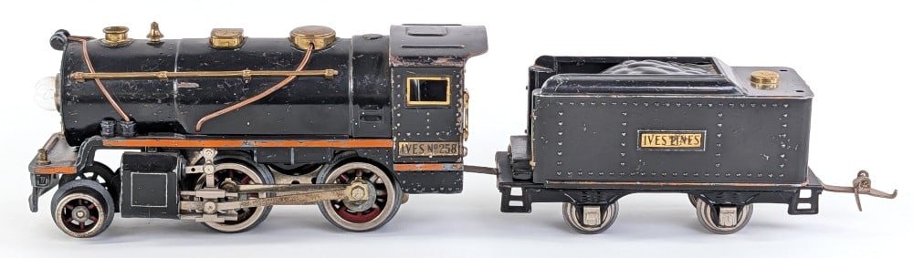 Ives No. 258 Locomotive with 257T Tender: Ives No. 258 locomotive with 257T tender. Locomotive has Lionel motor. The tender is missing the rear railing. It shows paint loss and wear from use and age.