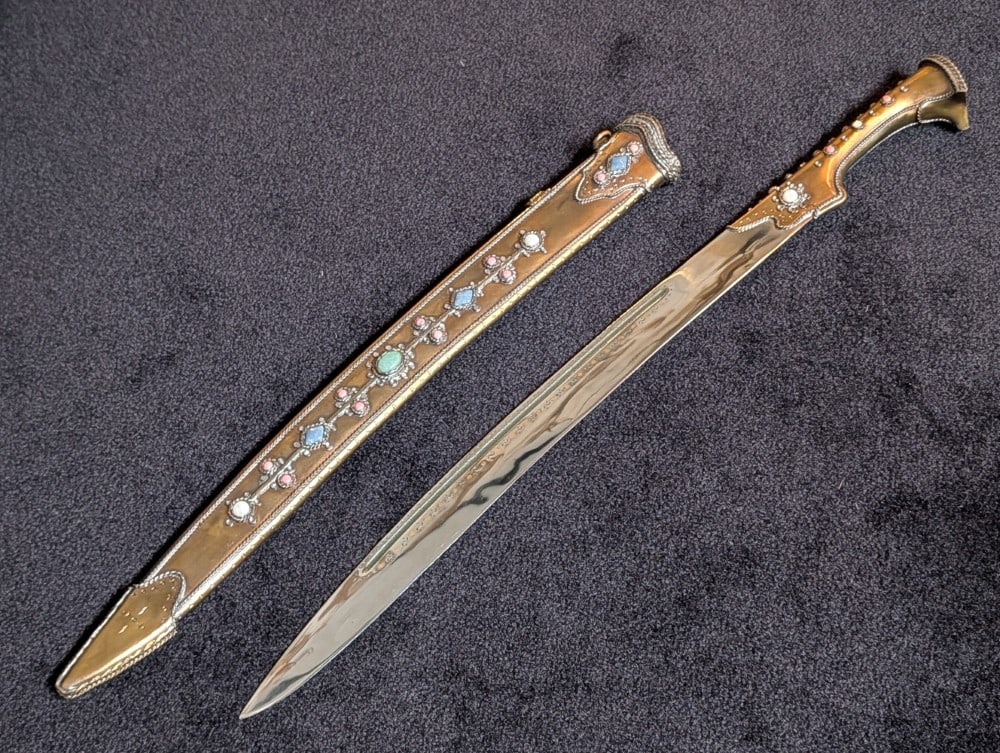 Ornate Turkish Yattagahn Sword w/ Scabbard: Features a mirror polished blade with what appears to be a makers mark, brass guard and handle frame with twisted brass and agate stone accents, and a brass butt cap with more stones. The scabbard is
