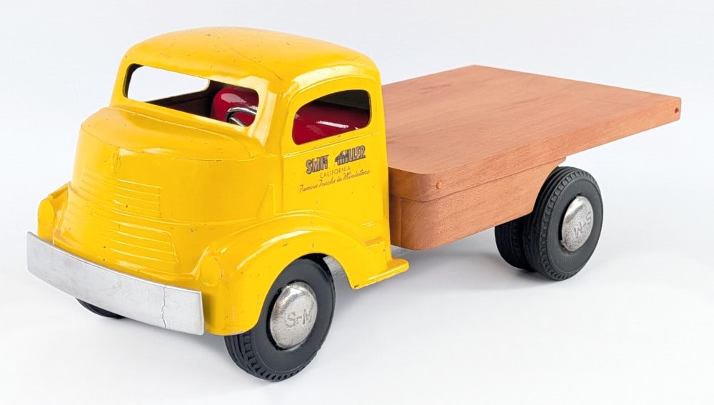Smith Miller GMC FLatbed Truck: Smith Miller GMC flatbed truck. The truck has a custom wood flatbed and custom interior. The front bumper has a crack in it and the truck shows some paint loss and decal loss. Measures approximately 1