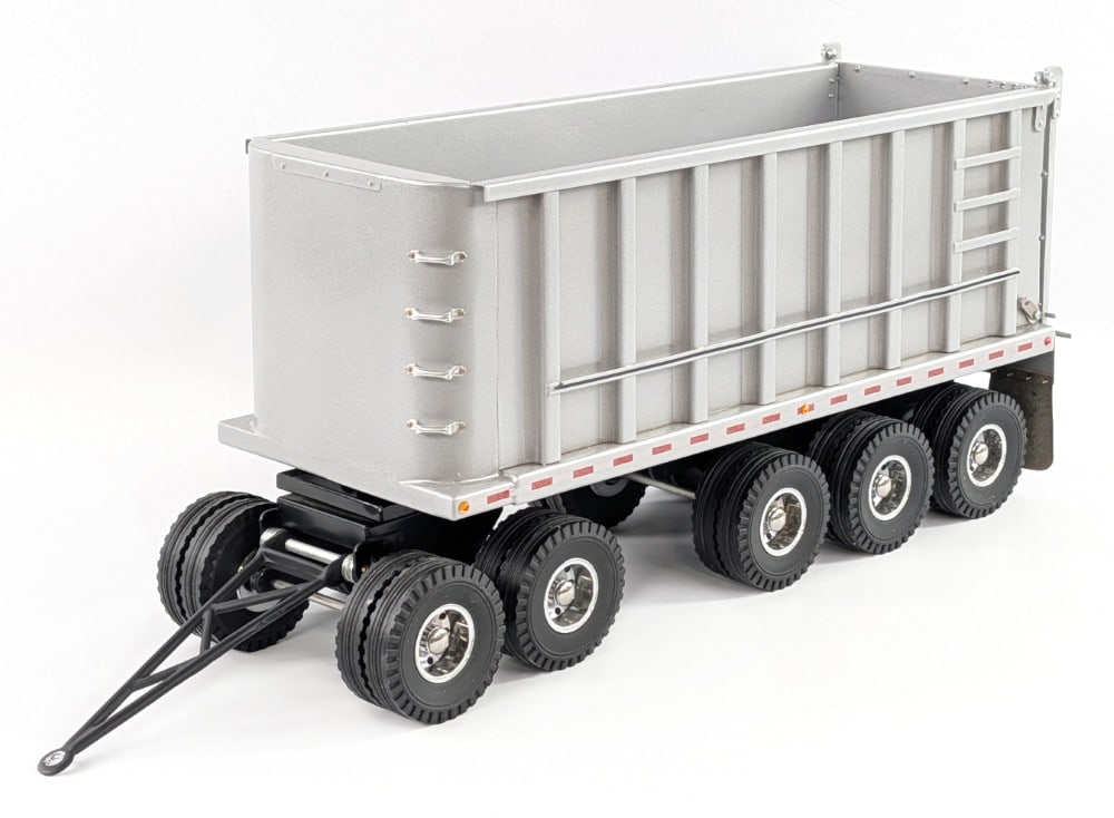 M&J Custom Dump Trailer: M and J custom tri-axle dump trailer. The trailer is made of metal and has chrome wheels, reflectors, and mudflaps. The trailer manually dumps and has a support so it can stay up. The rear gate on