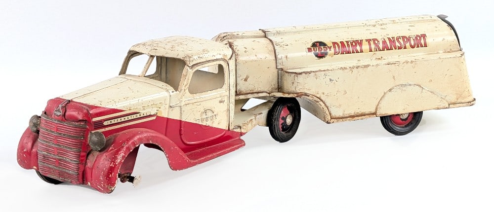Buddy L International Dairy Transport Tanker Truck: Buddy L International Dairy Transport tanker truck. The truck is missing the driver side front wheel and the door on the trailer was replaced. The truck shows paint loss and wear from play and age. Me