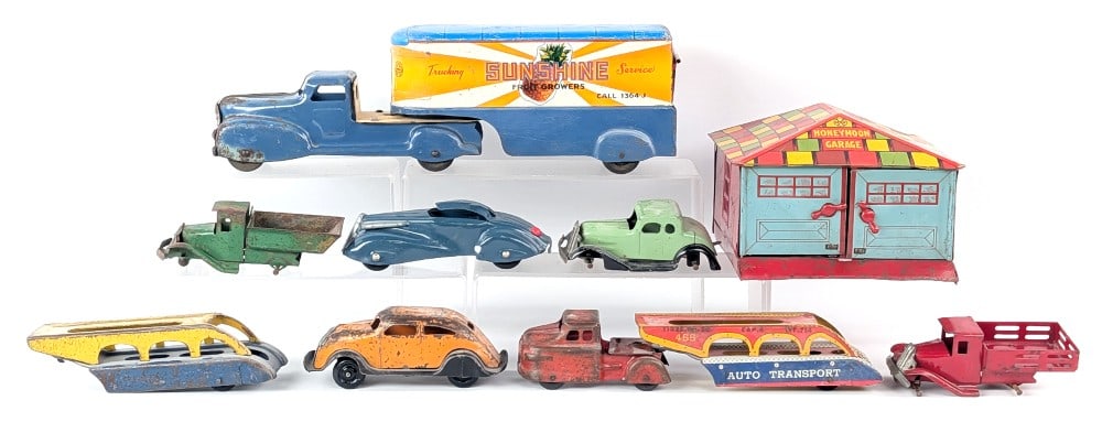 Marx Trucks, Automobiles, and Honeymoon Garage: Marx Sunshine Fruit Growers truck and trailer, car carriers, automobiles, trucks, and Honeymoon Garage. All showing paint loss, some missing wheels, and wear from age. The blue convertible is repainte