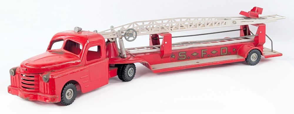 Structo Fire Department Aerial Ladder Fire Truck: Structo Fire Department aerial ladder fire truck. The truck is missing the steering wheel for the rear seat that rests on the ladder. The truck shows paint loss and wear from age. Measures