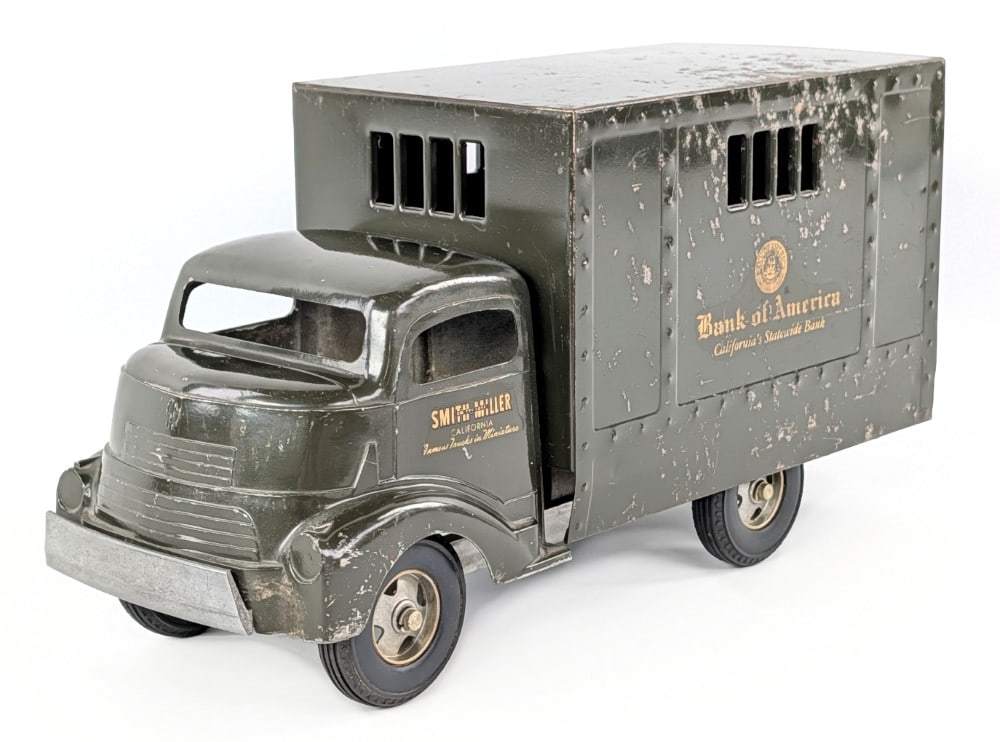 Smith Miller GMC Bank of America Truck: Smith Miller GMC Bank of America truck. The truck has a broken front bumper. It shows paint loss, crazing, and wear from play and age. Measures approximately 14" long.