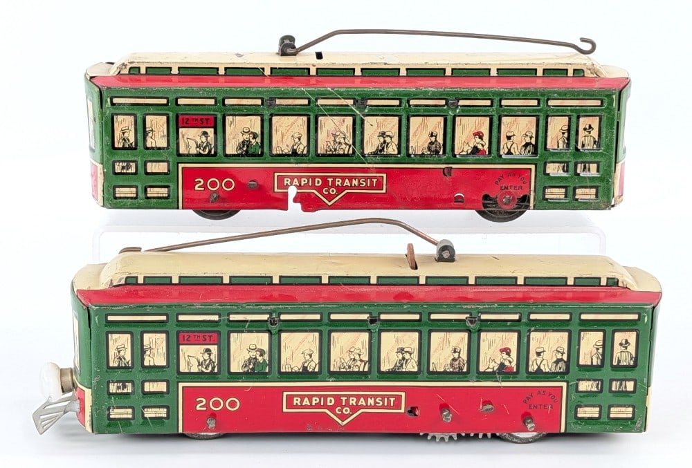 (2) Marx Tin Windup Rapid Transit Co. 200 Trolley Cars: (2) Marx tin litho windup Rapid Transit Co. #200 trolley cars. Fits on O Gauge track. The one is the deluxe version with battery operated headlight and cattle catcher. The one has a working windup